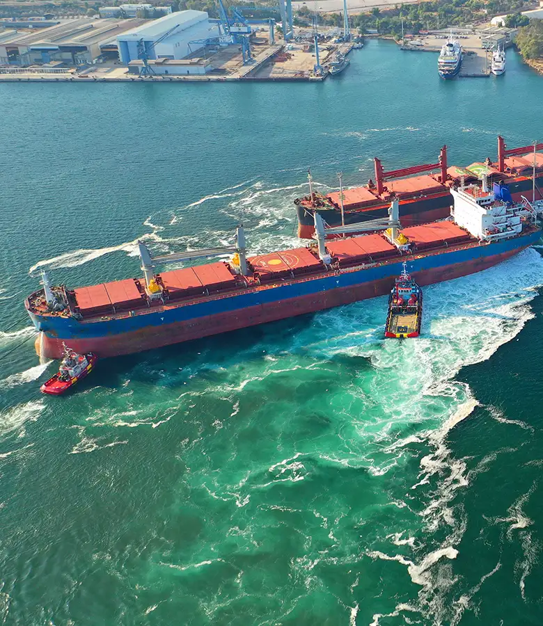 Aerial view of bulk carrier vessel with tugboats representing Universal Minerals Inc global iron ore shipping operations
