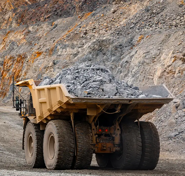 Mining haul truck loaded with raw iron ore at an open-pit mine face representing UMI's high-grade magnetite iron ore sourcing and supply service