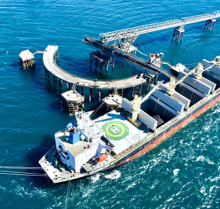 Aerial view of offshore conveyor loading arm over a bulk carrier ship representing UMI's end-to-end iron ore bulk shipping services