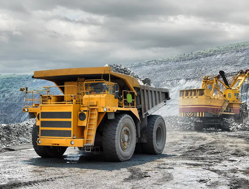 Heavy haul truck and excavator at open pit iron ore mine representing Universal Minerals Inc magnetite iron ore supply